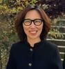 Image of Sandra Kim wearing black glasses and a black cardigan with gold buttons